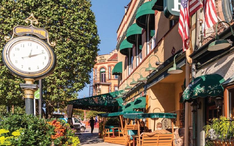 a sidewalk with a clock and stores